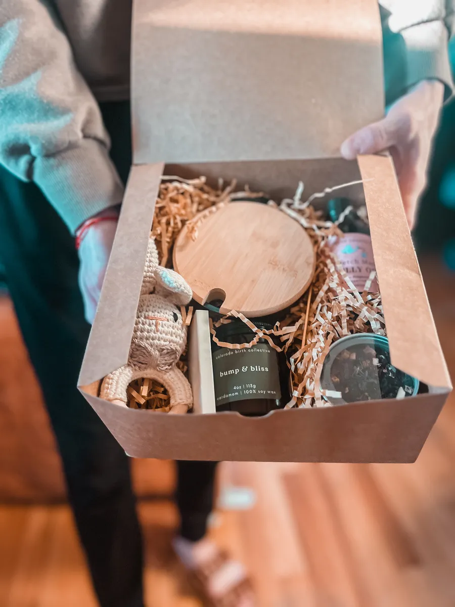 A gift box with a handmade candle and curated pregnancy treats